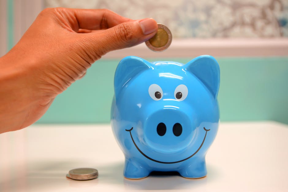 Hand inserting a coin into a blue piggy bank for savings and money management