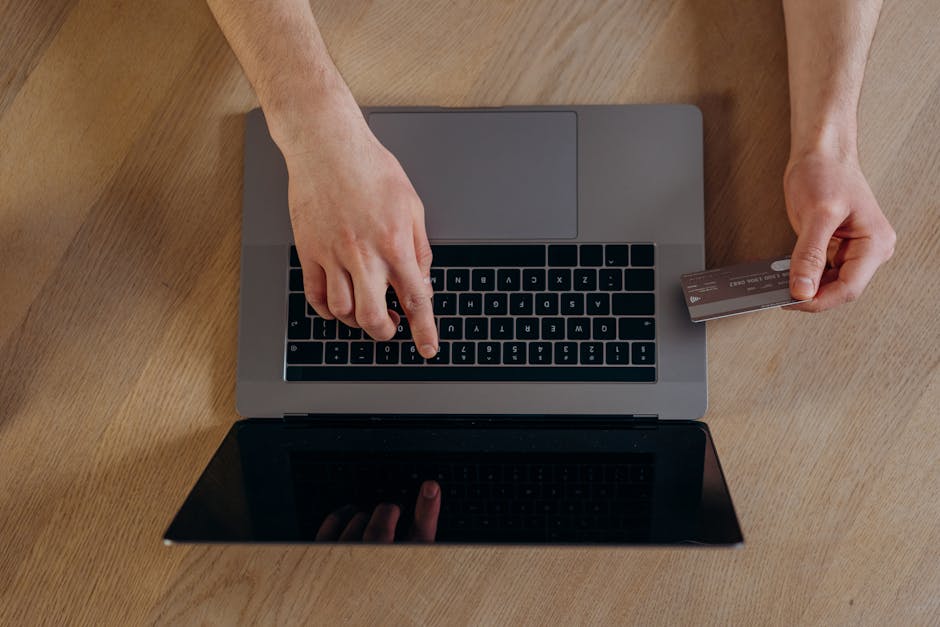 Top view of hands using a credit card and laptop for online transactions on a wooden surface